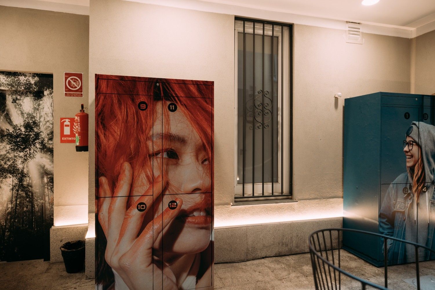 Galería de arte con grandes lienzos de retratos, incluyendo un rostro pelirrojo y una figura de tonos azules, en una sala.
