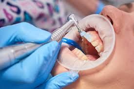 Dental assistant smiles next to a monitor showing dental x-rays in a dentist's office.