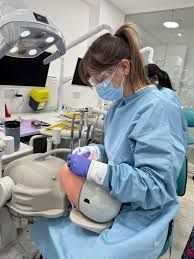 Woman in black sweater smiles beside dental x-ray screen. Dental office setting.