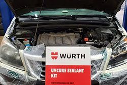 Car engine bay with a Wurth UV Cure Sealant Kit; hood up, ready for repair.