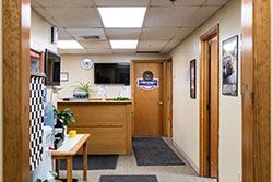 Hallway with a wooden reception desk and door, leading to an office.