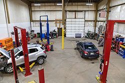 Interior of a car repair shop with vehicles on lifts, tools, and equipment.