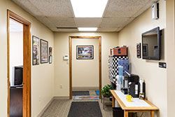 Hallway with doors, pictures, coffee station, and two flat-screen TVs on the wall.