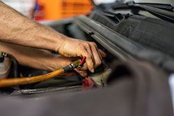 Hands of mechanic working on car engine, holding a tool.