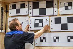 Man adjusting calibration targets on a wall. Targets are black and white checkerboards.