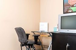 Office corner with chair, desk, computer, and poster on tan walls.