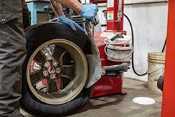 Mechanic in blue gloves, inflating a car tire on a tire machine in a garage.
