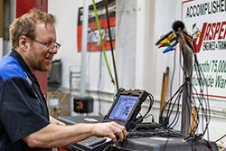 Mechanic using a laptop computer to diagnose a vehicle in a repair shop.