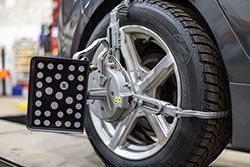 A car wheel with alignment equipment attached, in a garage setting.