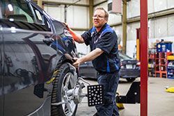 Mechanic aligns a car tire in a garage, using equipment.