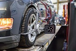 Car being aligned on a lift in a garage, sensors attached to the tires.