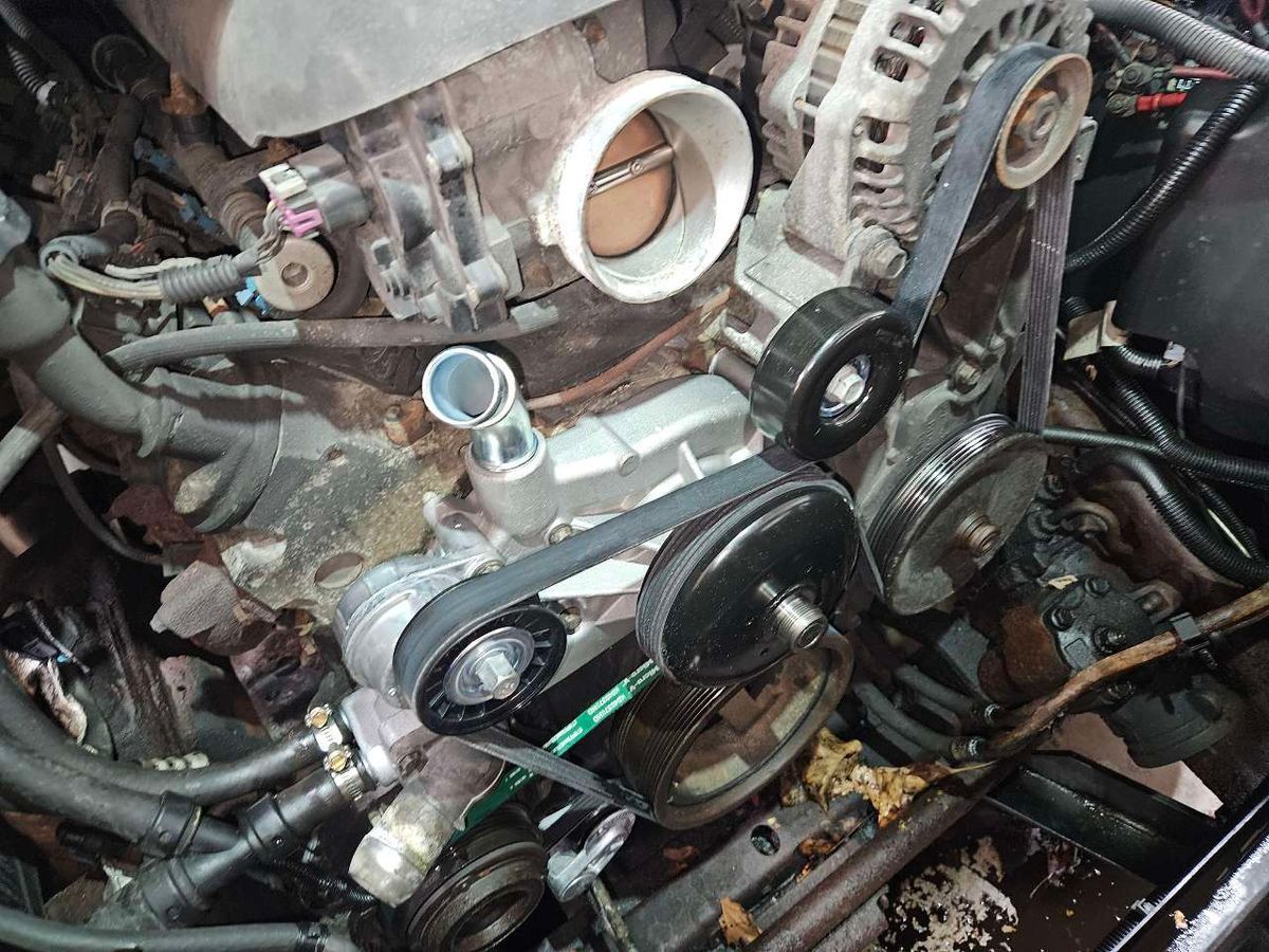 Car engine with belt and water pump visible. | Accomplished Automotive