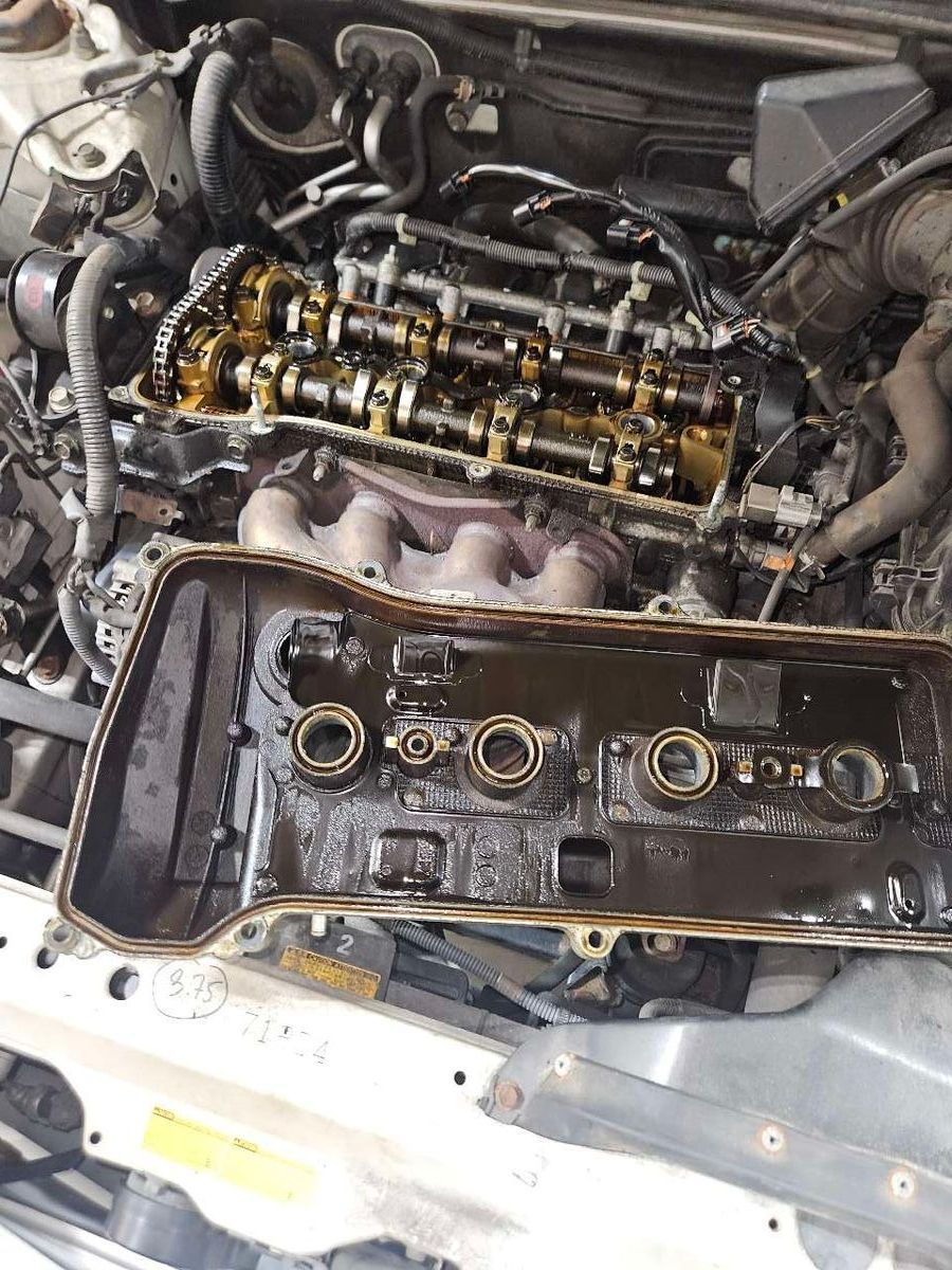Open car engine with removed valve cover, showing oil and mechanical components. | Accomplished Automotive