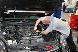 Mechanic working on a car engine in a garage. | Accomplished Auto