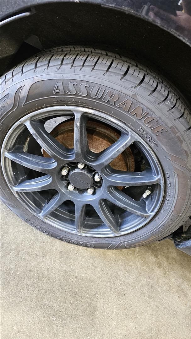 Black car tire with Assurance logo on a black rim.