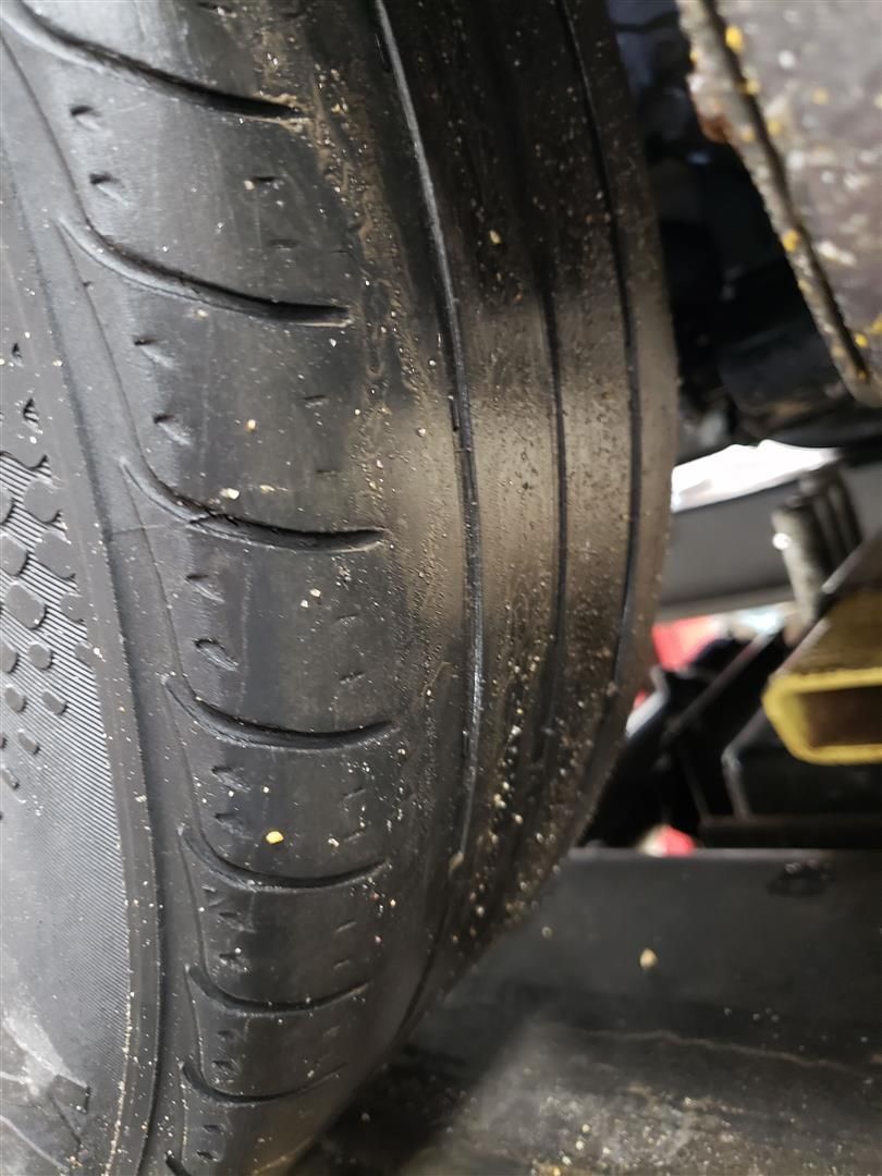 Close-up view of a car tire, showing the tread pattern and wear.