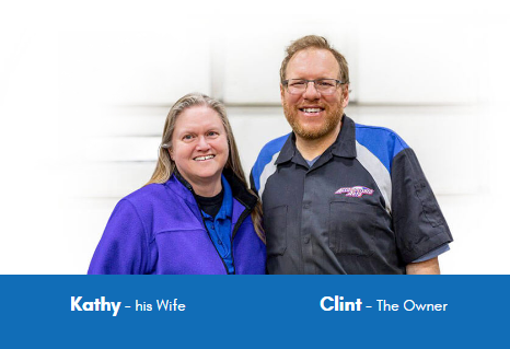 Two people, Kathy and Clint, smiling in front of a white background. Kathy is wearing a purple jacket, and Clint is in a blue and black mechanic shirt.