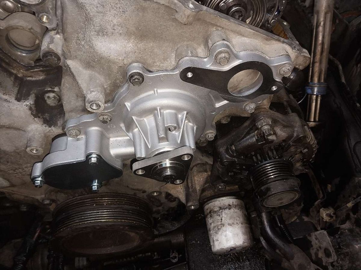 New water pump installed on a vehicle engine, with gray and black components. | Accomplished Automotive