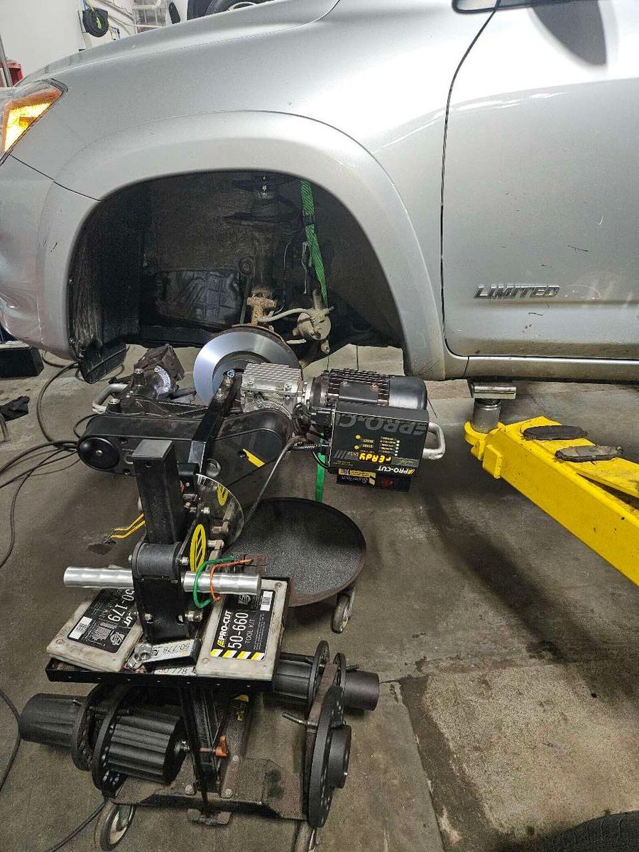 Car on a lift with a wheel alignment machine. Silver car, black machine, yellow lift. | Accomplished Automotive