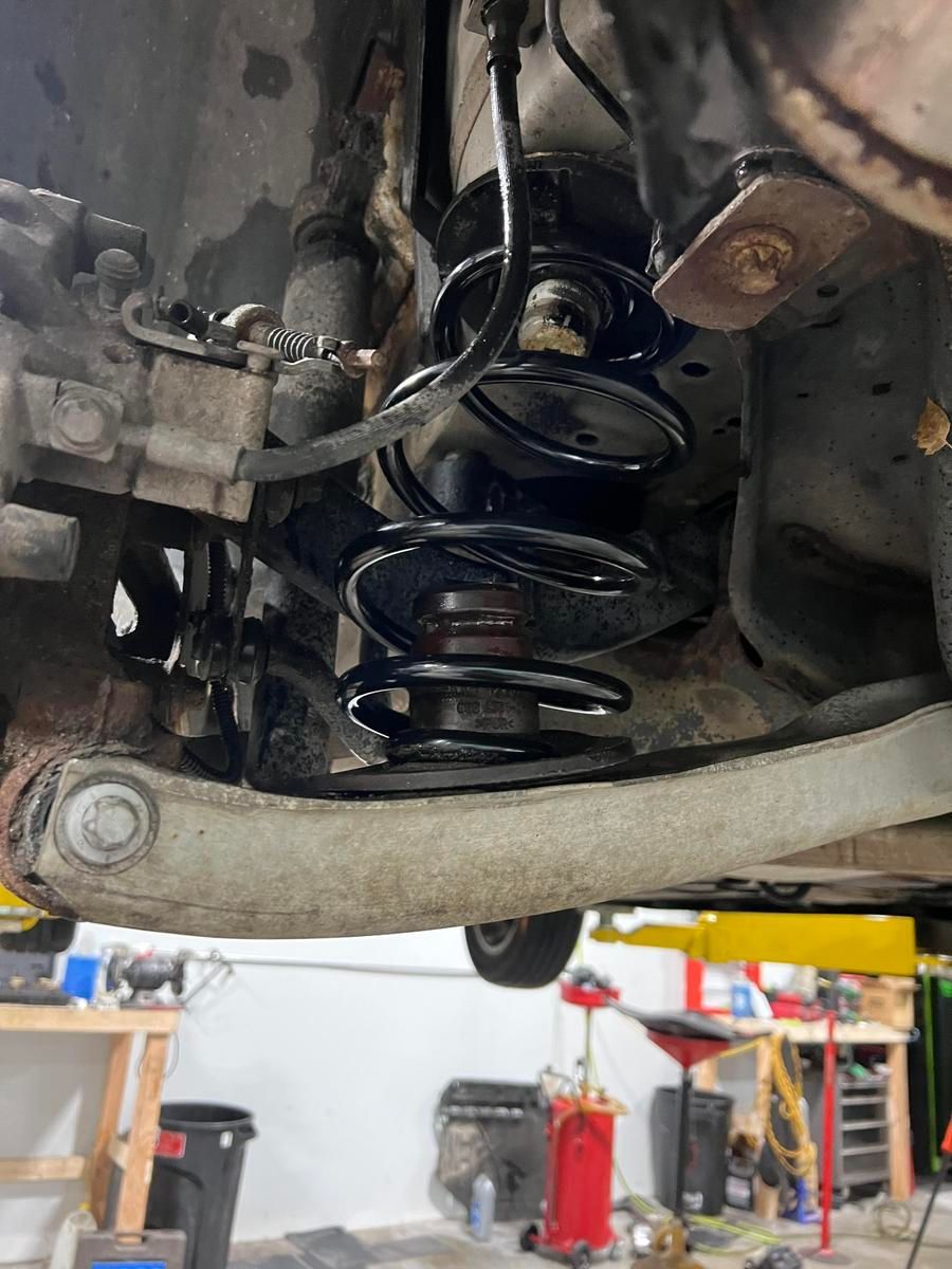 Rear suspension assembly of a car, showing the spring, shock absorber, and control arm. | Accomplished Automotive