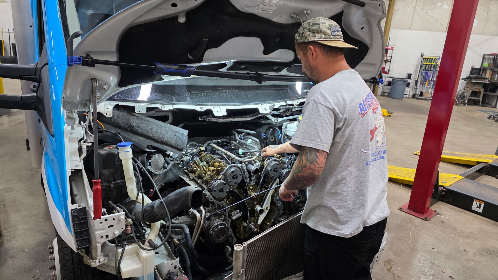Mechanic working on the engine of a van with the hood open in a garage. | Accomplished Automotive