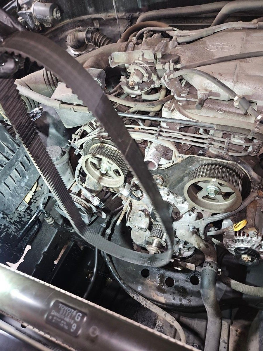 Car engine with timing belt exposed, pulleys visible. Gray metal and black belt. | Accomplished Automotive