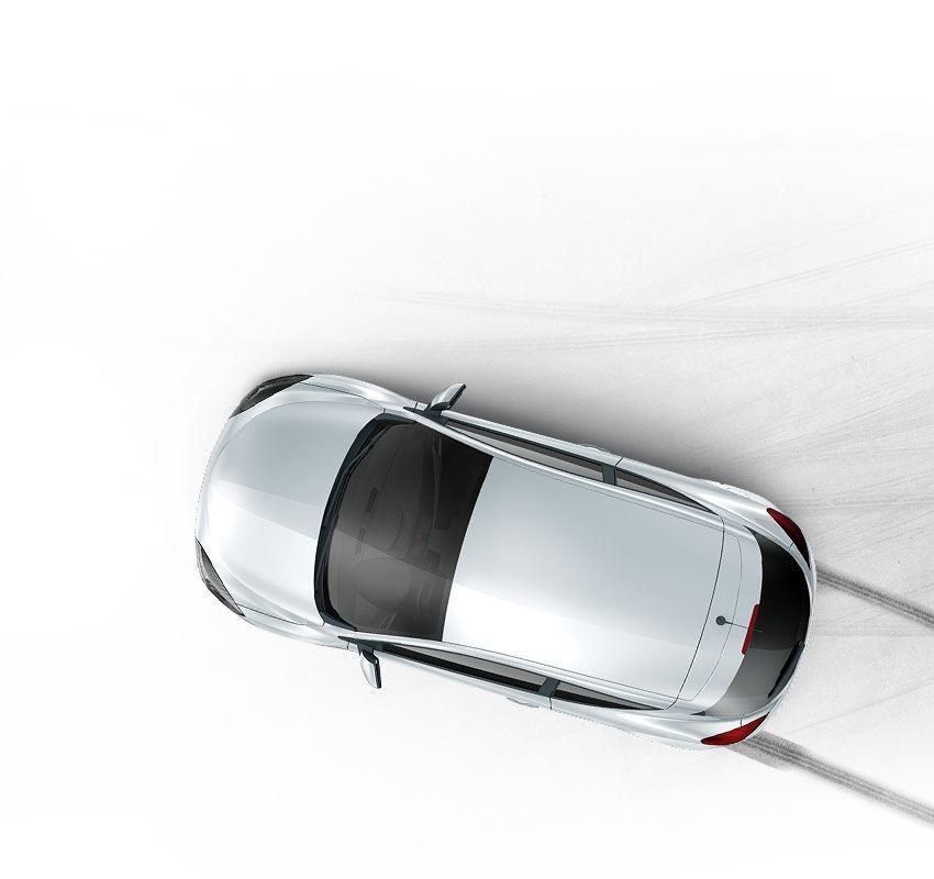 Top-down view of a silver car drifting on a white surface, with motion blur visible. | Accomplished Auto