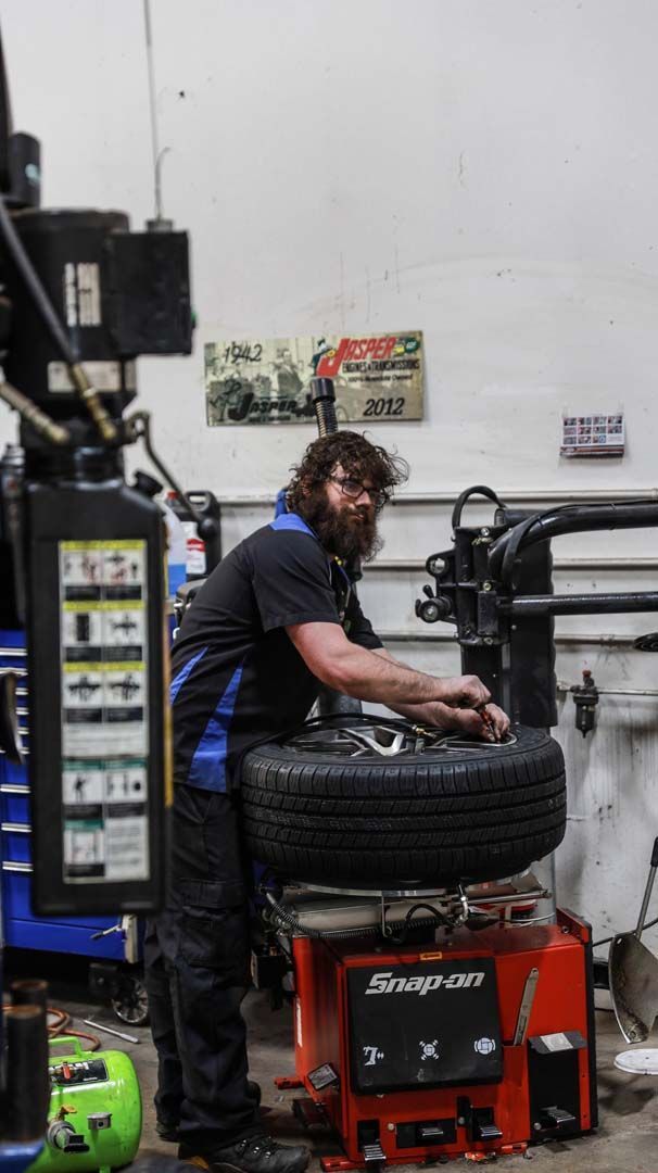 Mechanic working on a tire using a Snap-on machine inside a garage.