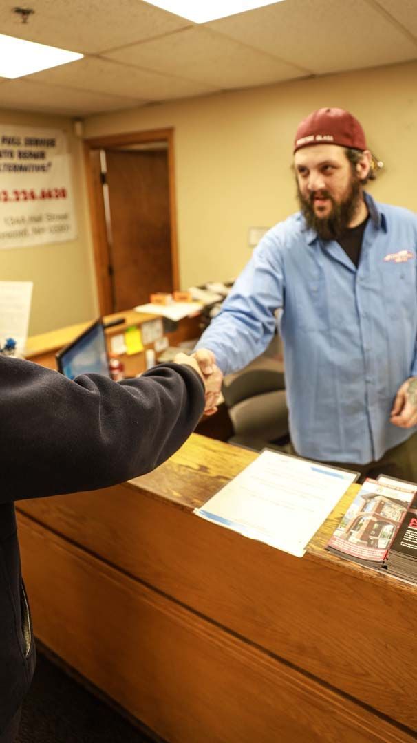 Man in blue shirt shakes hands at a service desk; a sign for 