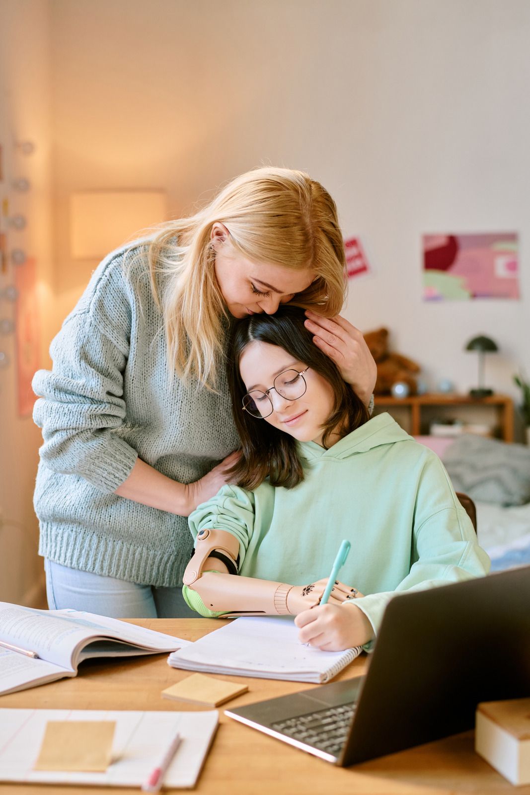 Two parrots on a branch by a thatched-roof shelter, surrounded by greenery.