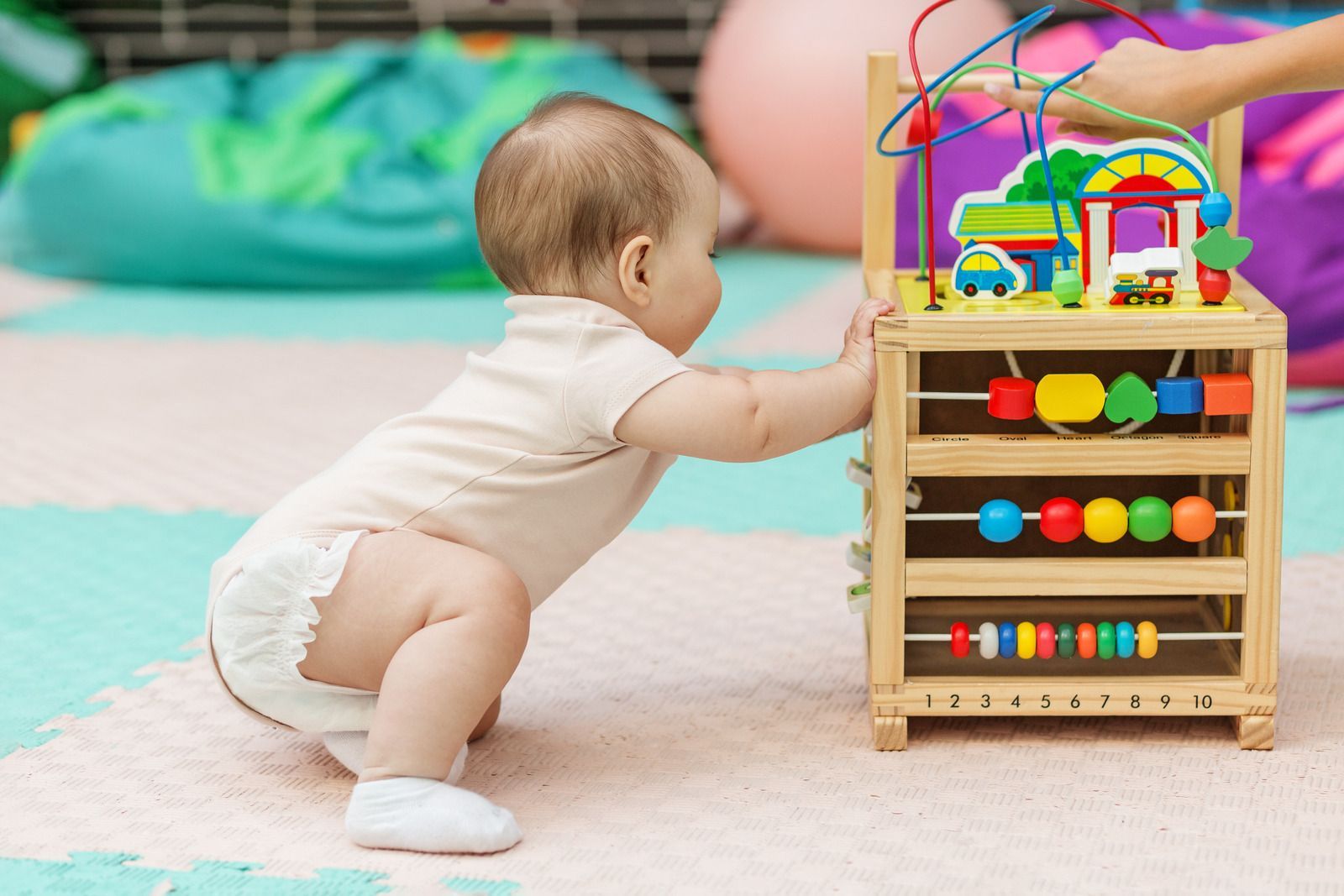 Baby playing with wooden activity center on a soft floor.