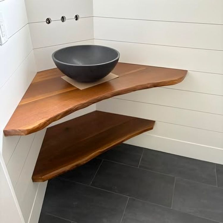 Corner bathroom shelves with a dark sink, against white paneled walls and dark tile flooring.