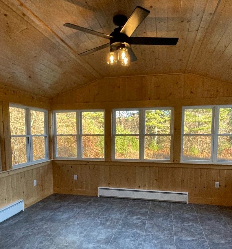 A room with a lot of windows and a ceiling fan