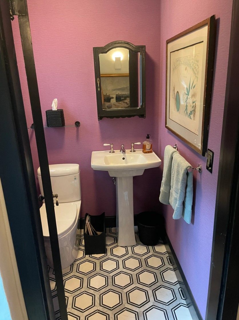 Small bathroom with purple walls, pedestal sink, hexagon tile floor, and framed art.