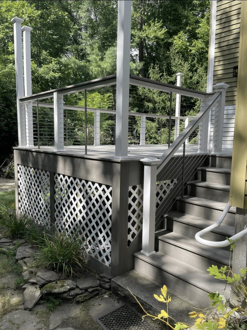 Gray painted wooden deck with lattice skirting and steps, white railing, and a small handrail.