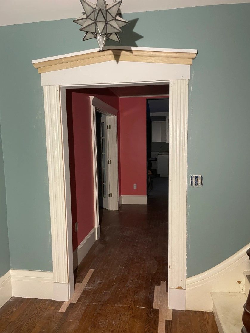 Doorway with white trim, leading to a hallway with red walls and wooden floor. Green walls surround the doorway.