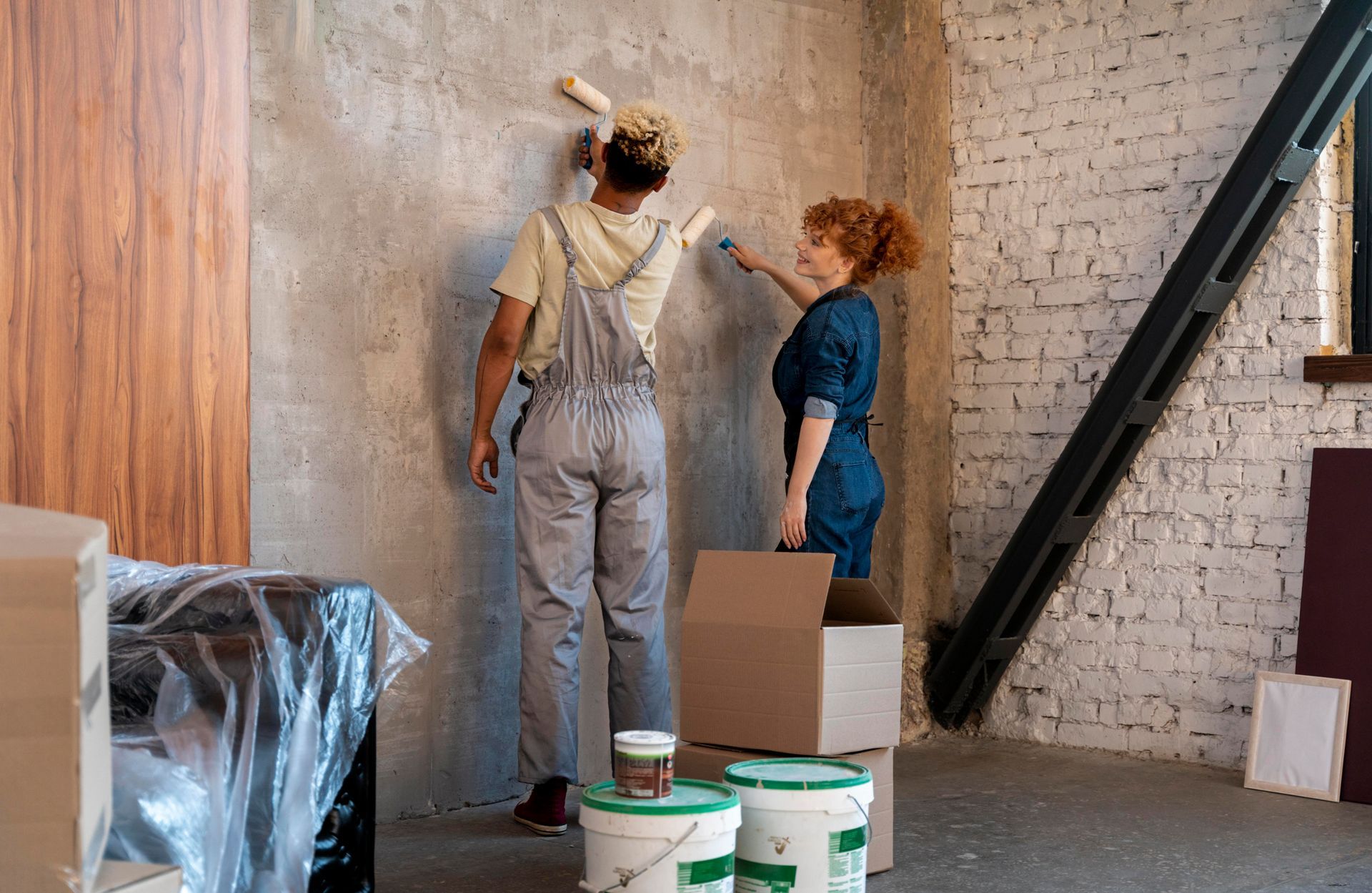 A man and a woman are painting a wall together.