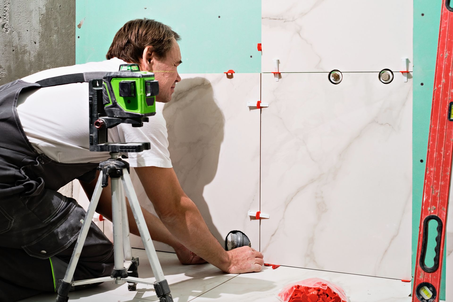 A man is measuring a tile floor with a laser level.