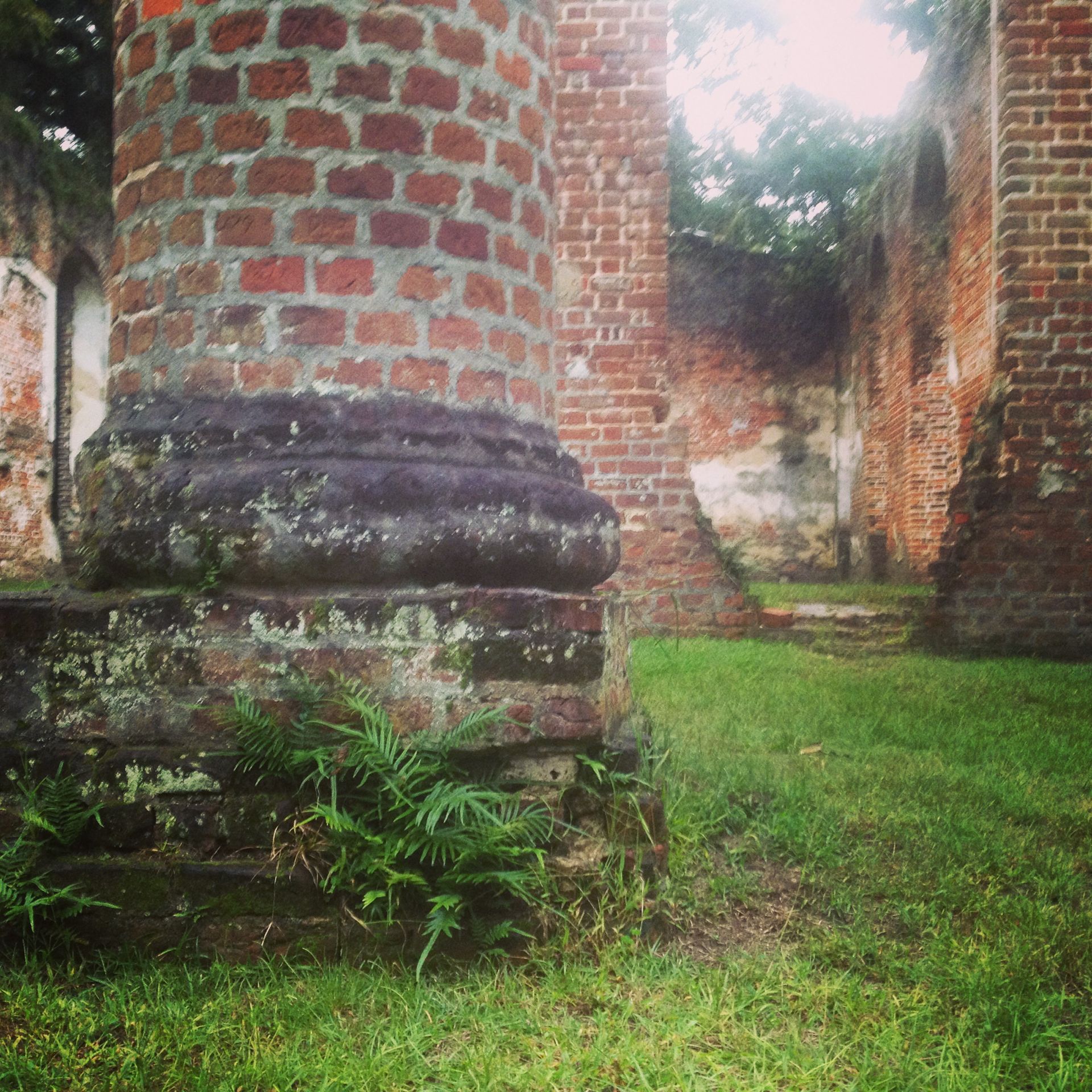 Sheldon Church, Ruined brick church interior; pillar in foreground, green grass and overgrown details.