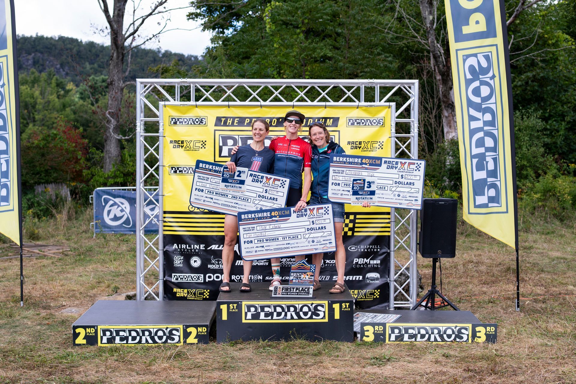Three people on a podium holding awards. They are in front of a banner that says 
