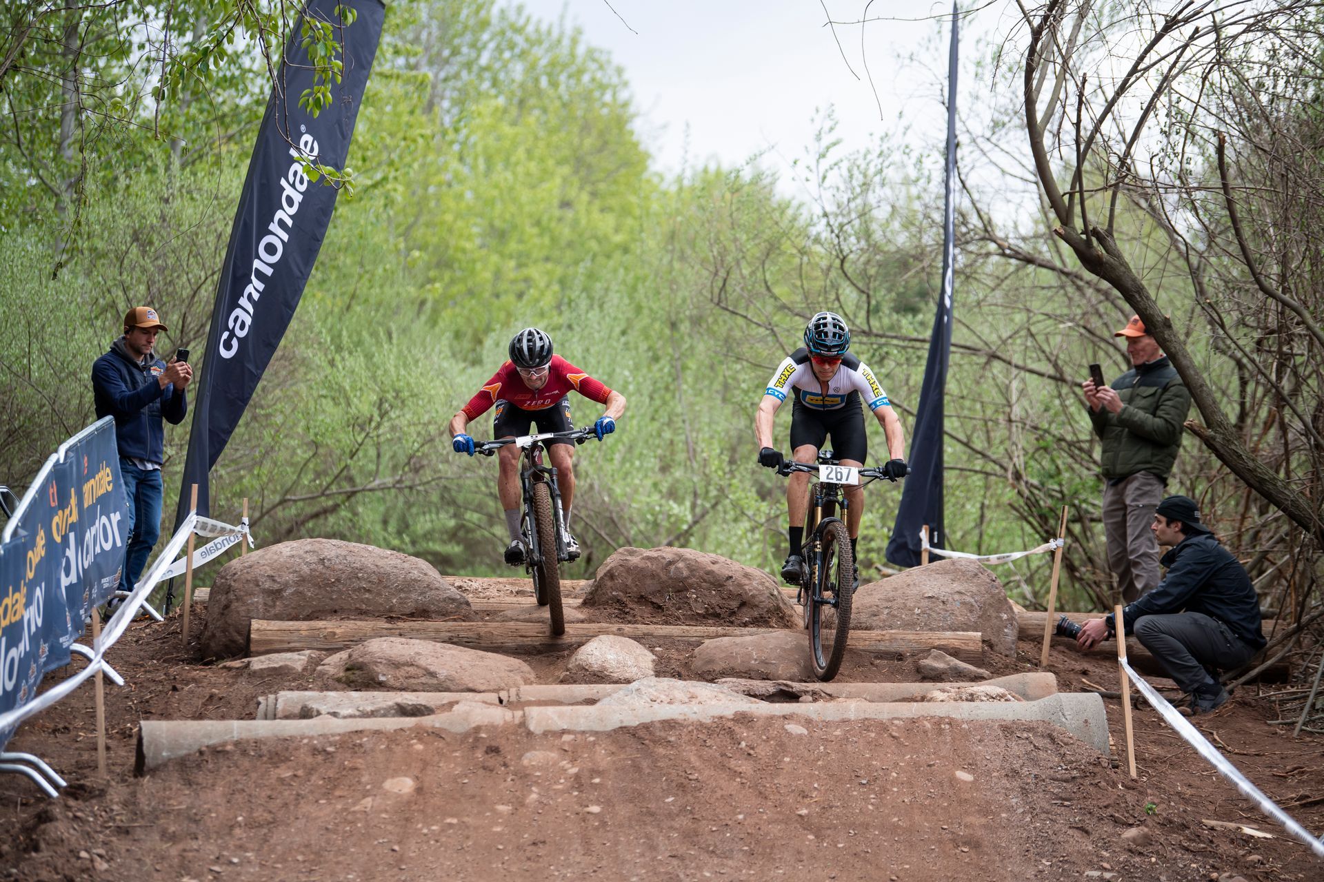 Two mountain bikers navigate a rocky obstacle course during a race.