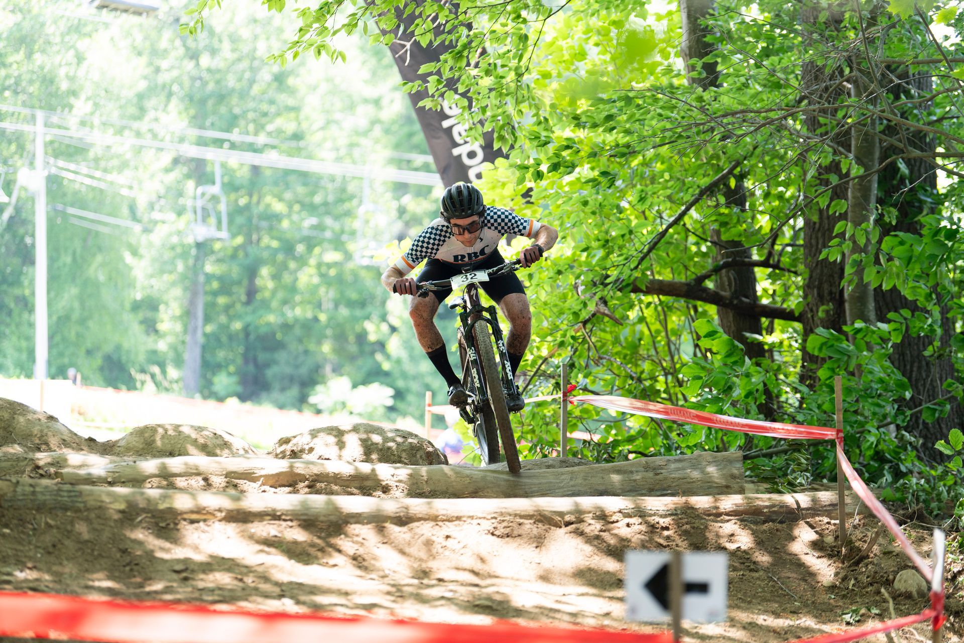 Mountain biker on a dirt trail, navigating steps. Surrounded by trees and foliage.