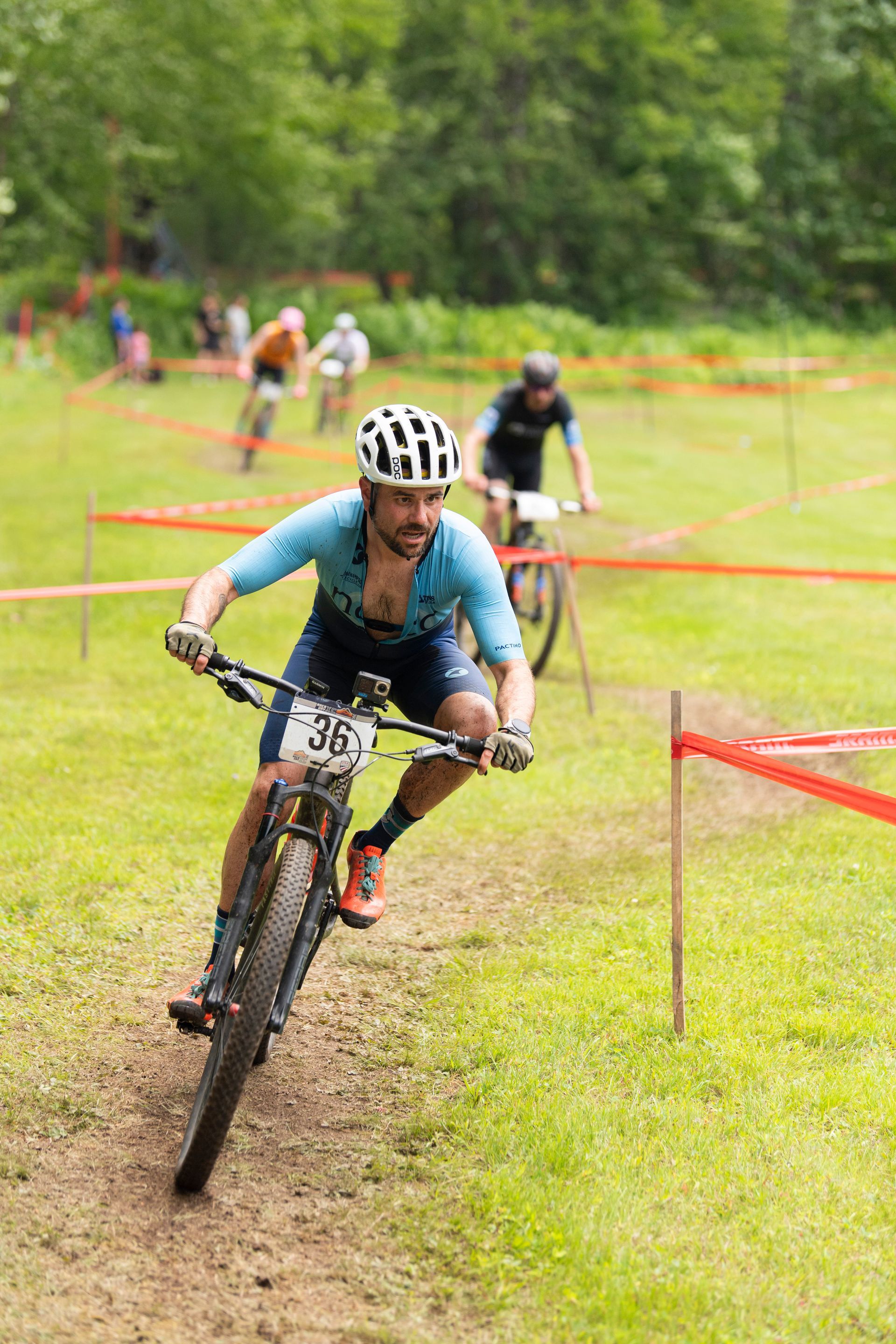 Mountain biker in blue jersey racing on a grassy course with red course markers.