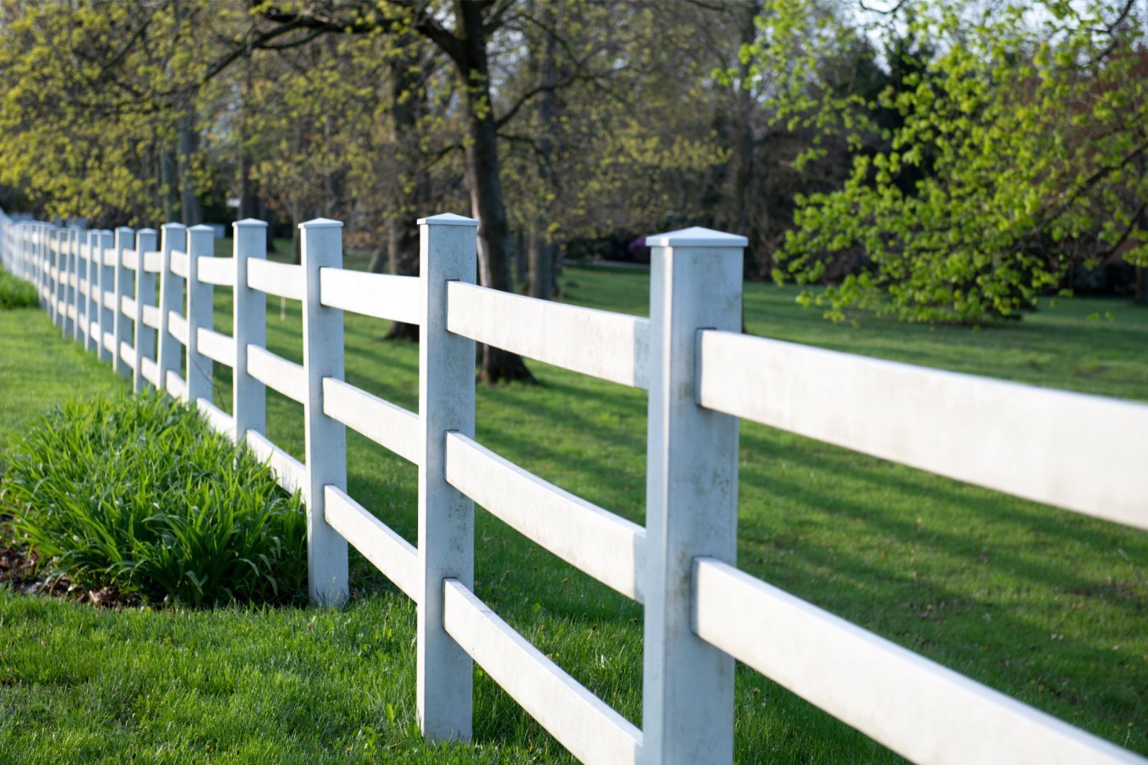 Image of a white split rail fence in a grassy lawn in Decatur, GA