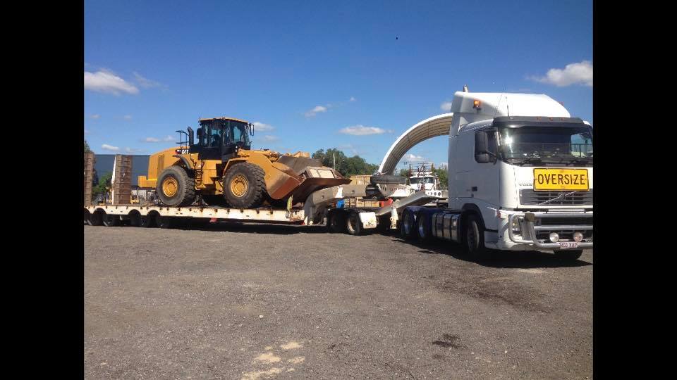 earth moving machine being transported on a heavy duty trailer