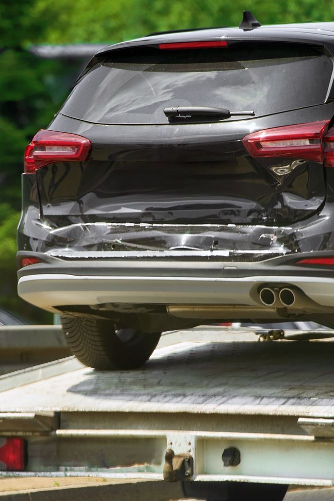 Black SUV on a tow truck, rear view with taillights visible.