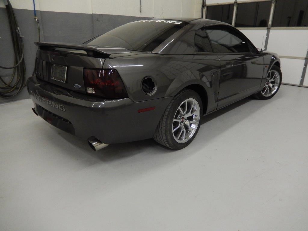 Dark gray Ford Mustang coupe in a garage, with tinted taillights and silver wheels.