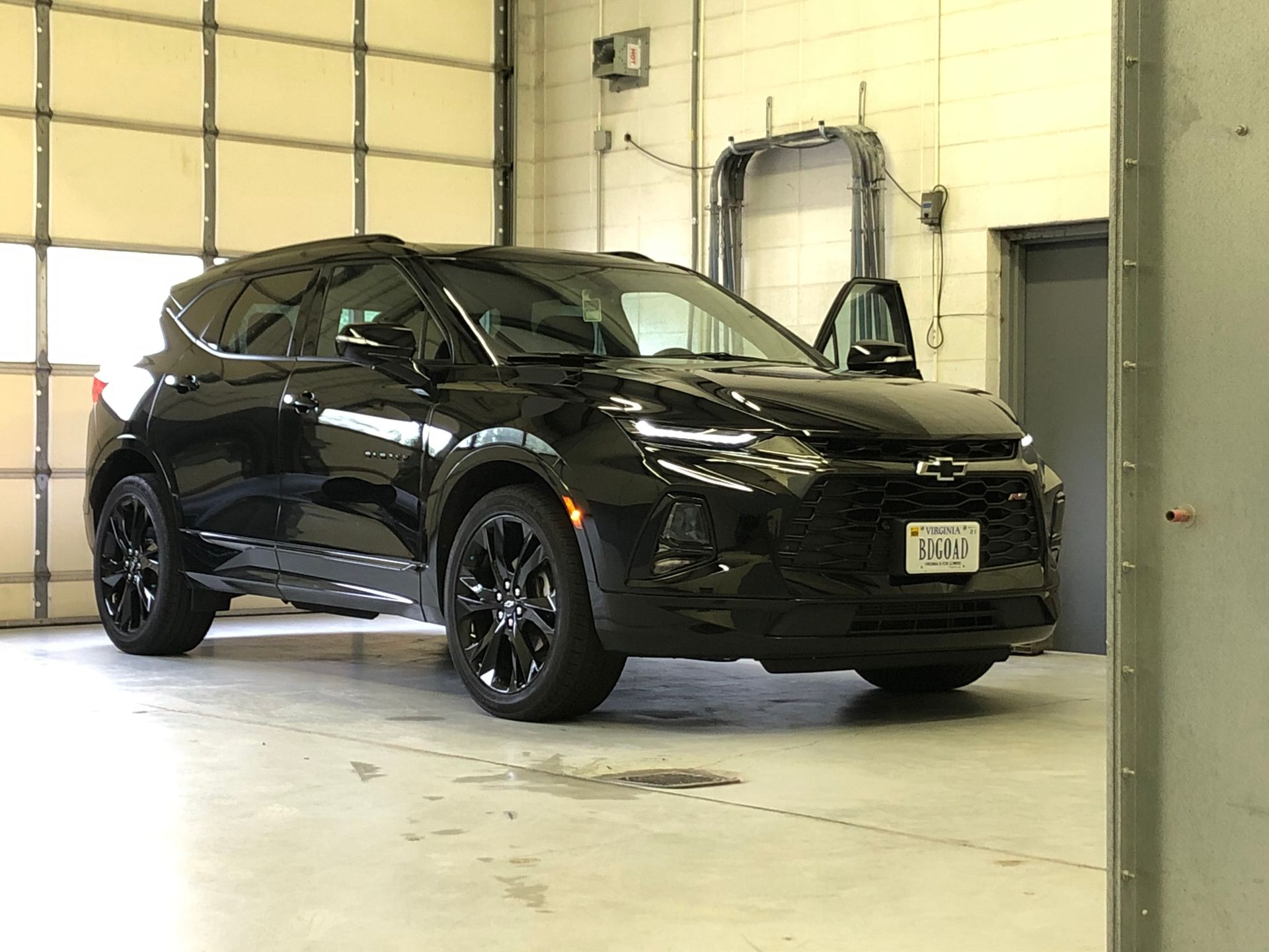 Black Chevrolet Blazer SUV parked in a garage with the door open.