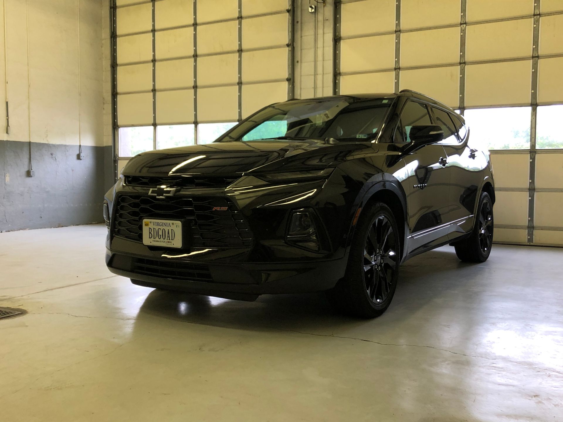 Black Chevrolet Blazer SUV parked inside a garage with the overhead door open.