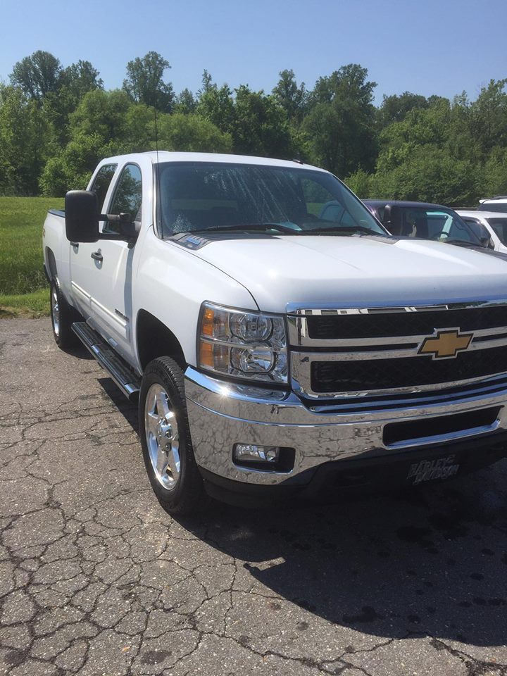 White Chevrolet pickup truck parked on cracked pavement, sunny day.